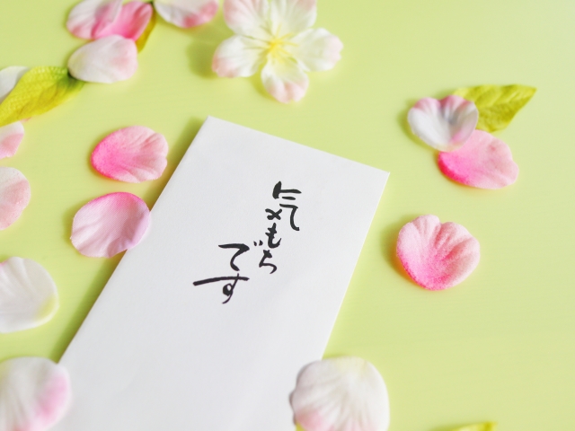 桜の花びらと「気持ちです」と文字の入った白い封筒