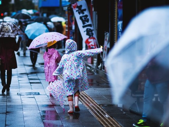 雨の日レインコートを着た子供が町なかを歩いている